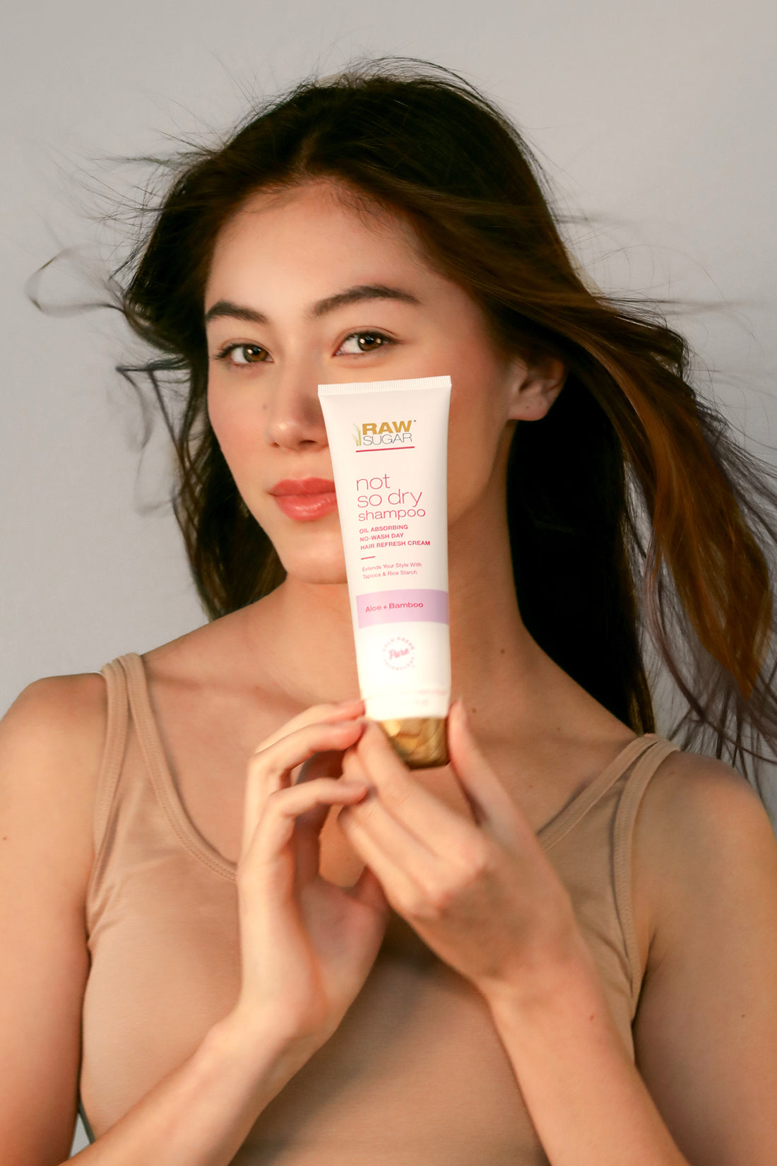 asian woman holding bottle of dry shampoo
