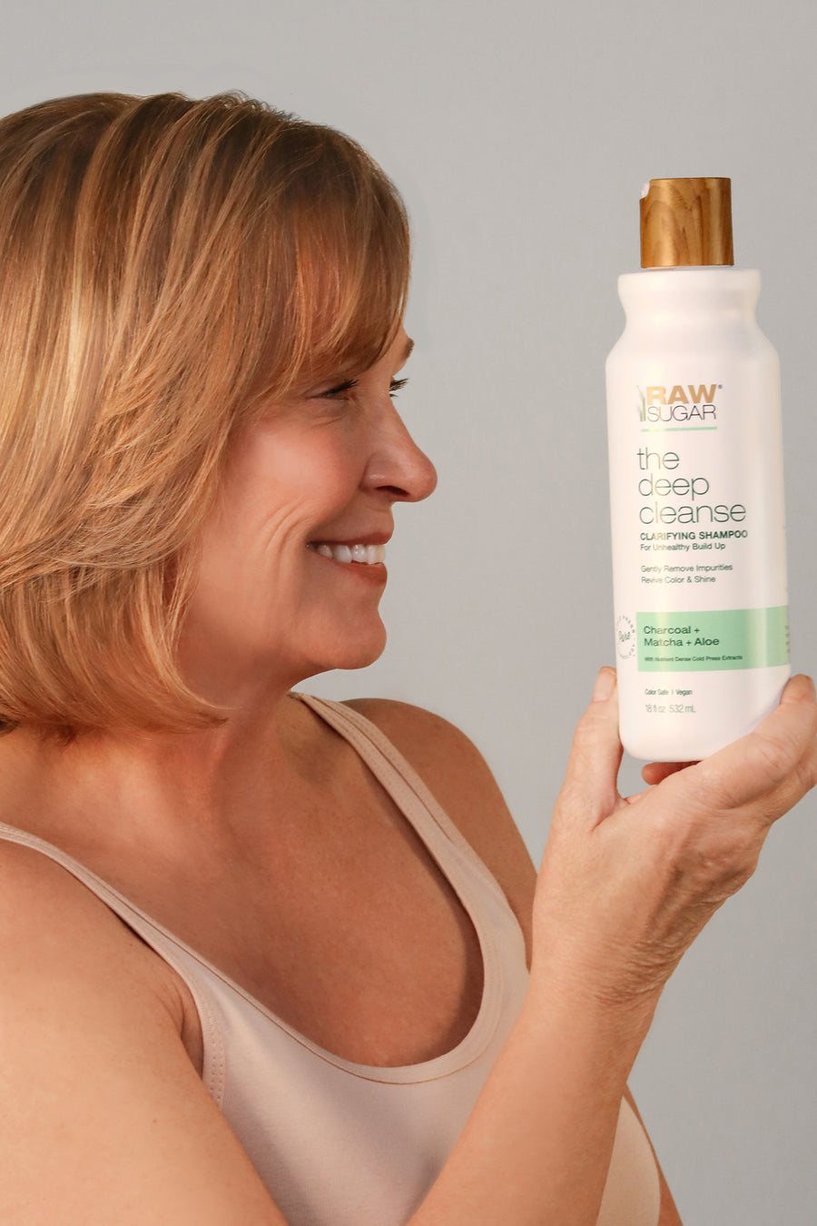woman smiling holding deep cleanse shampoo