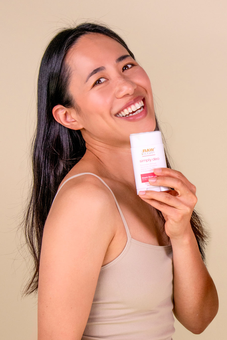 woman holding aluminum free deodorant and smiling