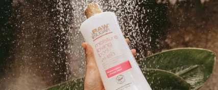 hand holding body wash in front of waterfall