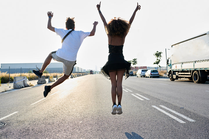 two people jumping for joy in middle of road outside