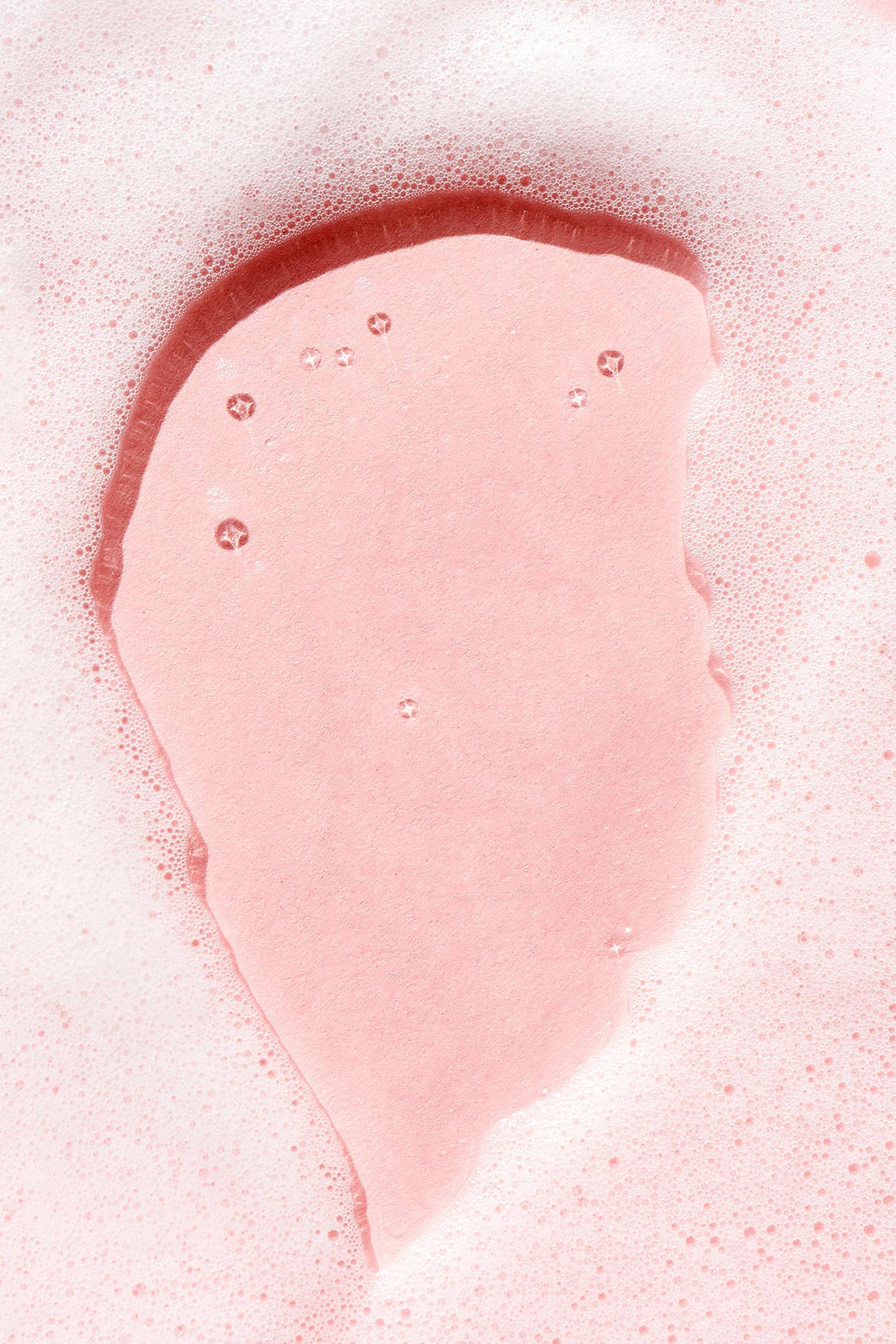 Sudsy white foam on a light pink background