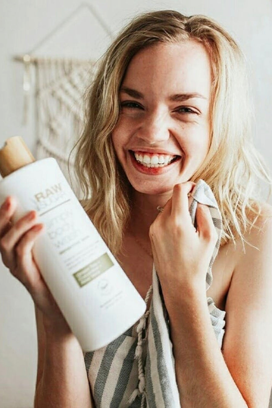 Smiling female holding a bottle ofSimply Body Wash for Sensitive Skin | Green Tea + Cucumber + Aloe Vera