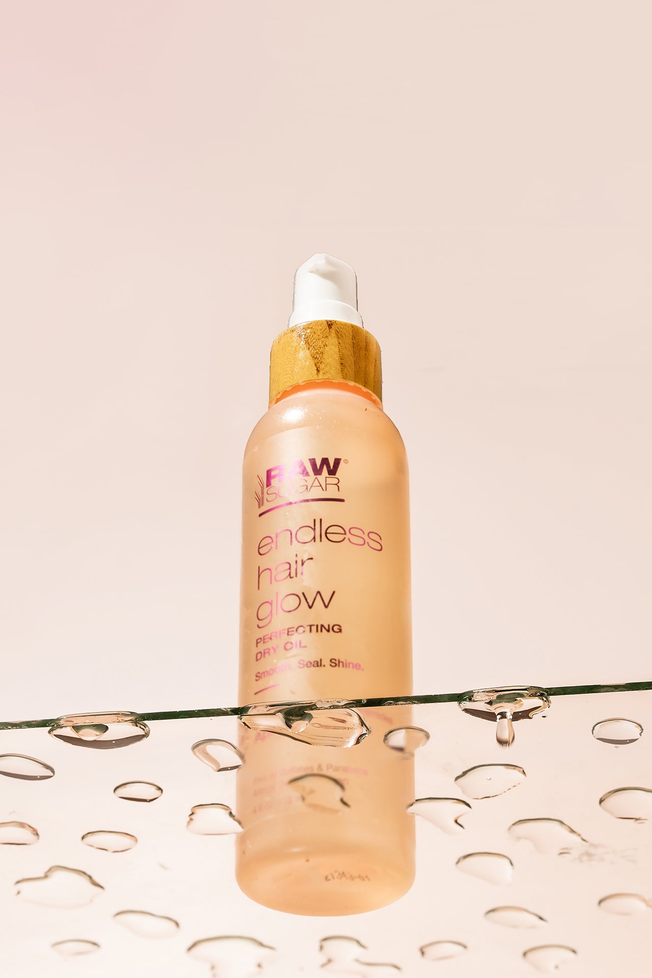 Endless Hair Glow bottle sitting on top of glass with beautiful water drops