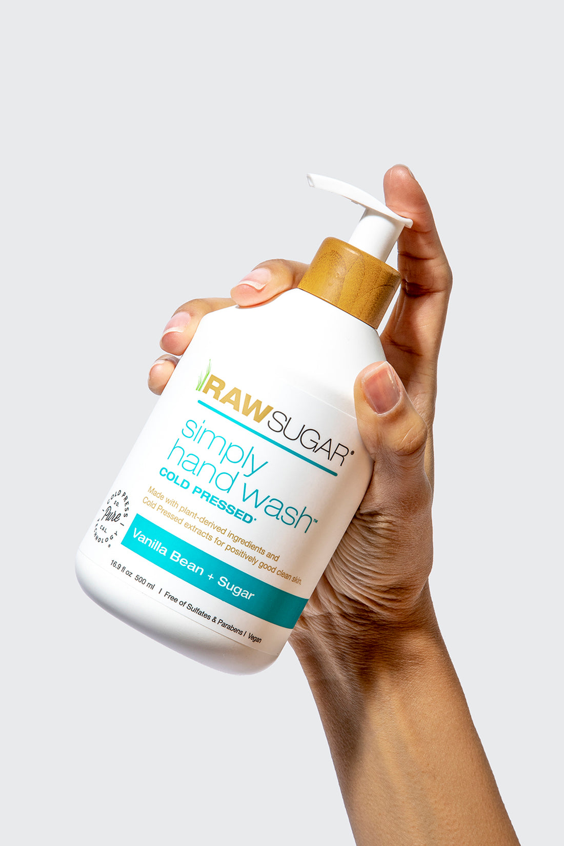 A hand holding a bottle ofSimply Hand Wash | Vanilla Bean + Sugar with a finger on the pump