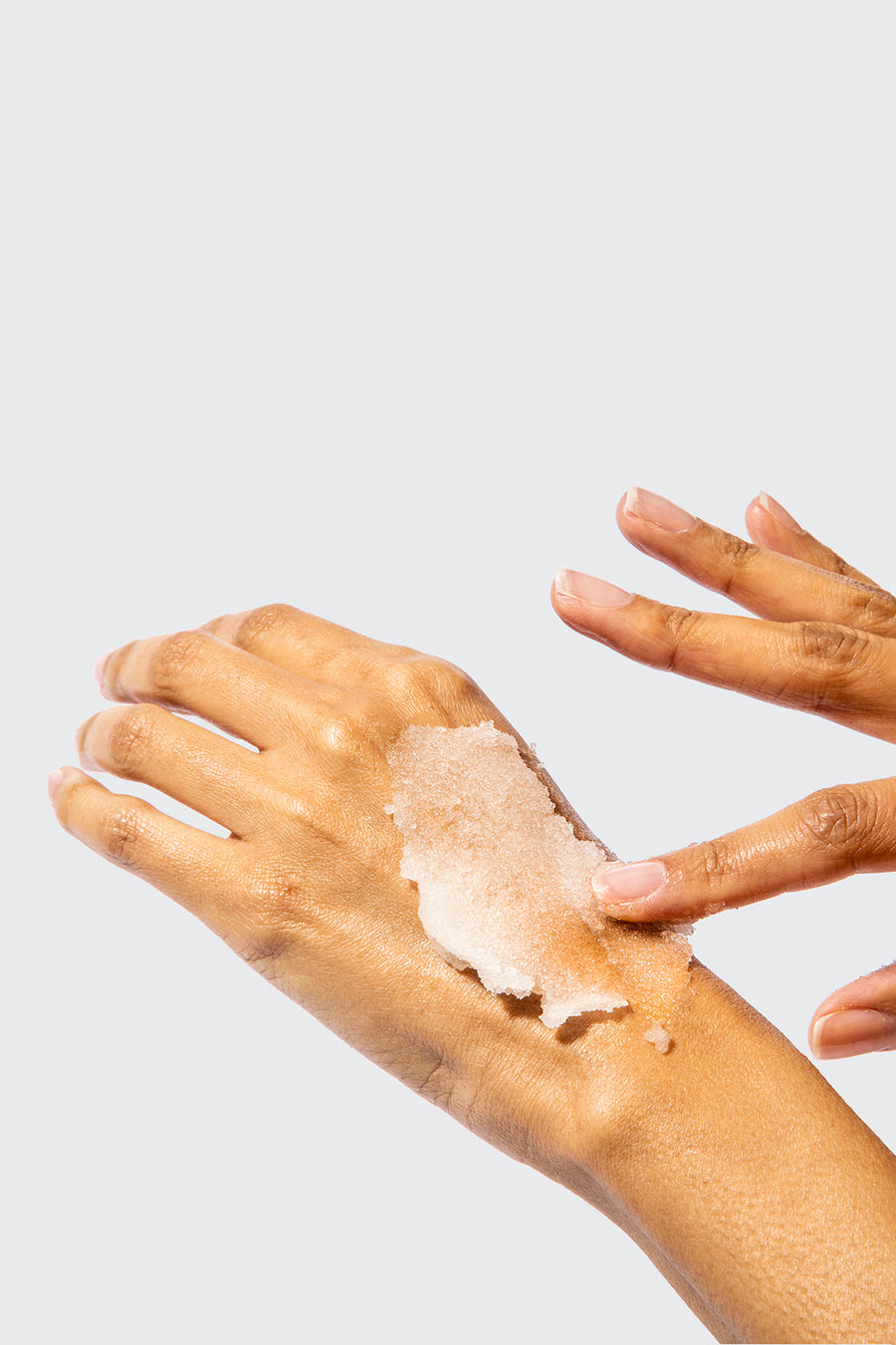 A pair of hands applying scrub to back of one hand