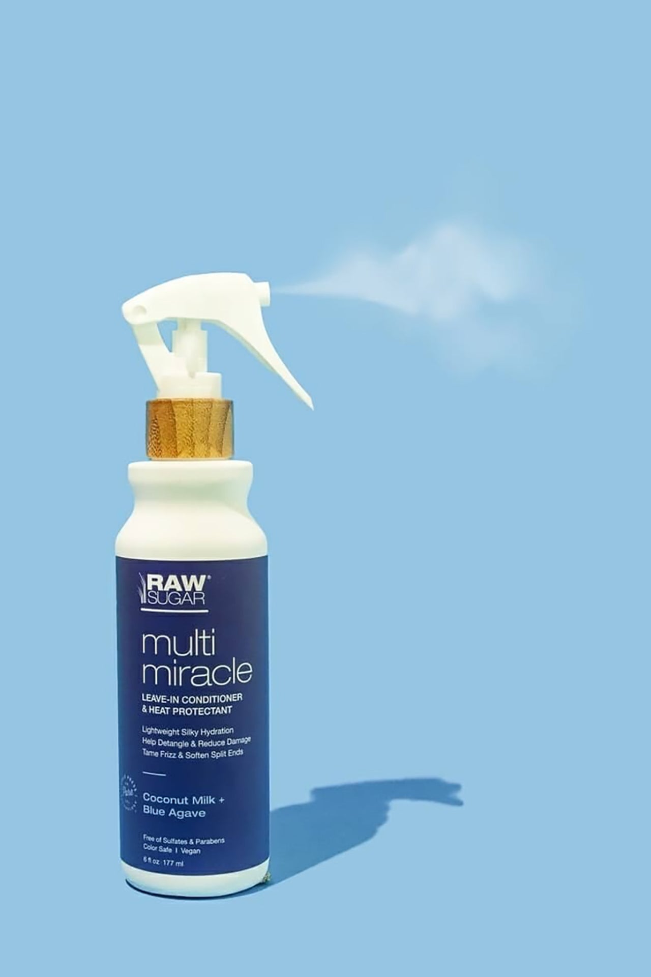 Raw Sugar Coconut Milk + Blue Agave Leave-in Conditioner + Heat Protectant bottle showing mist spray from pump with light blue background