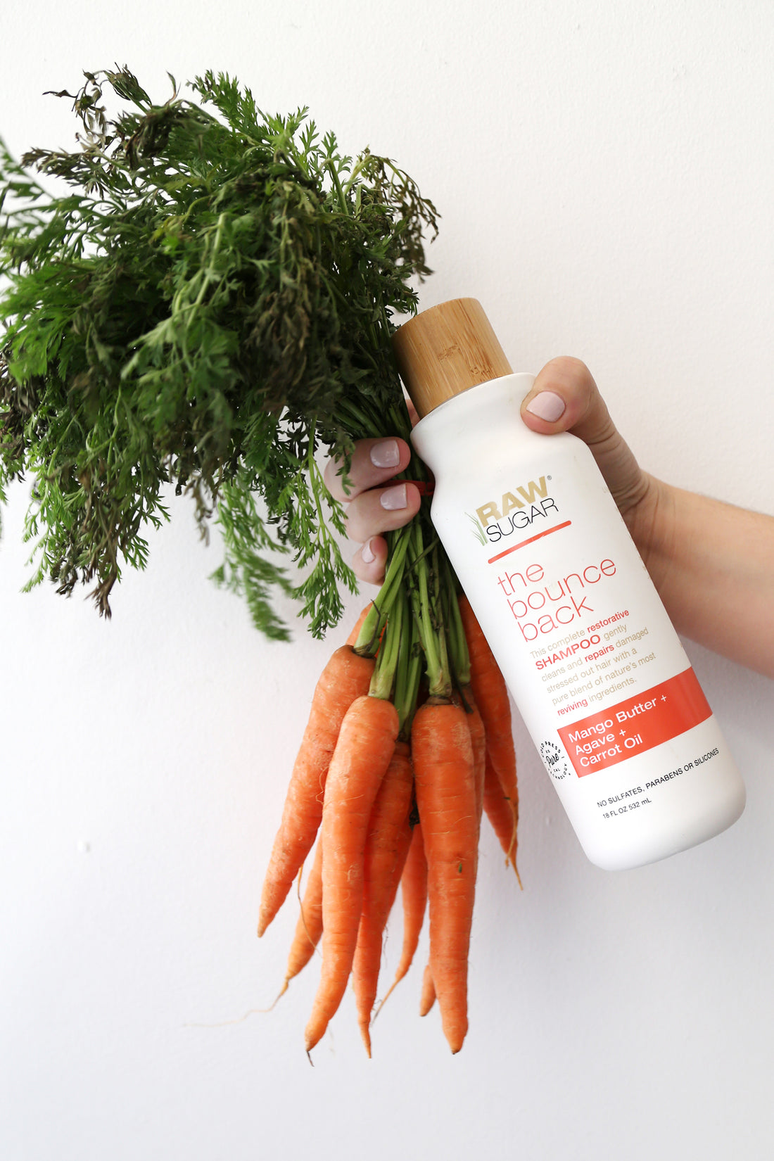 Hand Holding Bunch of Carrots and Shampoo