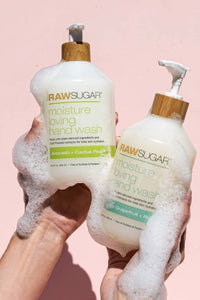 Hands holding up Raw Sugar Hand Wash with suds dripping down