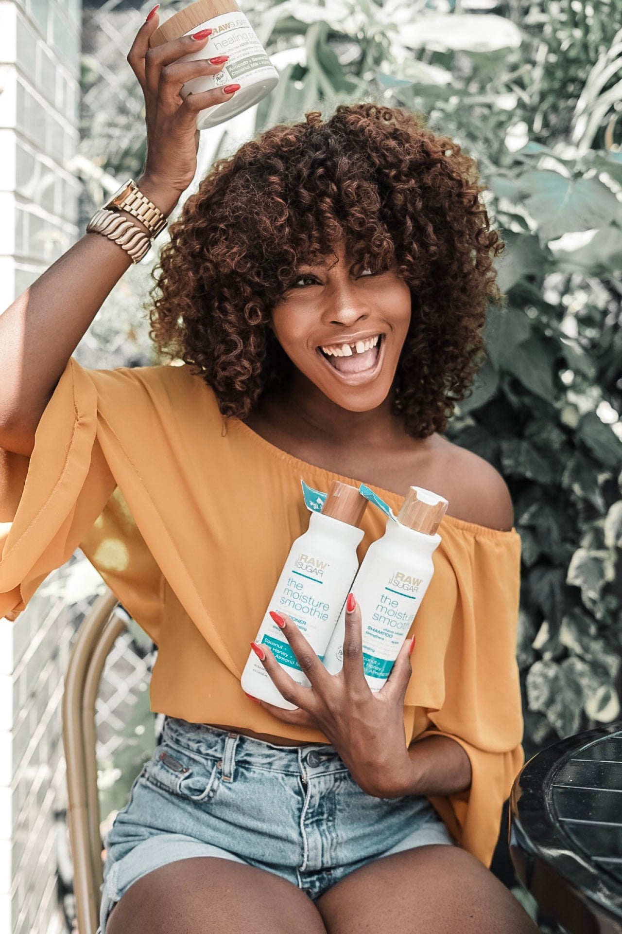 Woman holding Raw Sugar Shampoo, Conditioner, and Hair Masque.