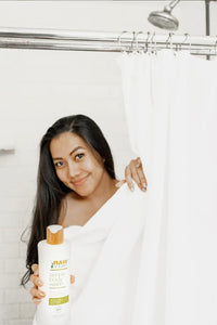 woman holding body wash in shower with long hair