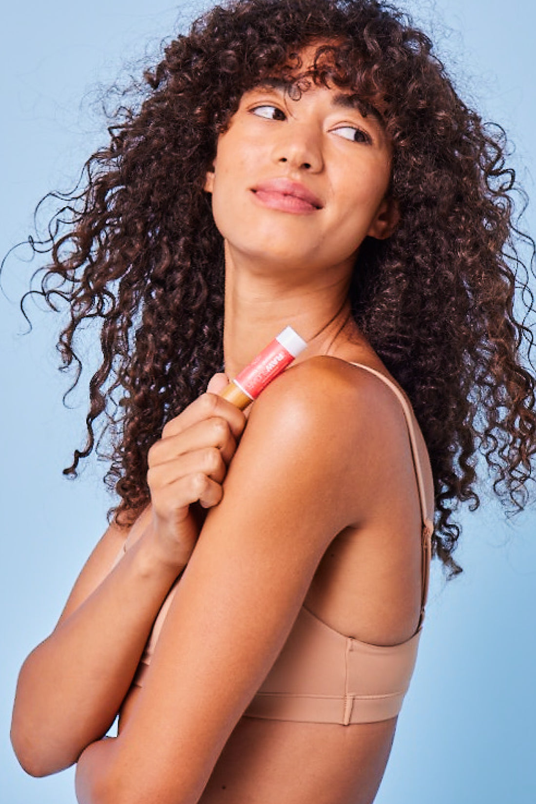 woman holding lip balm against blue background