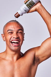 Man Holding Bottle of Shampoo and Squeezing Onto Head