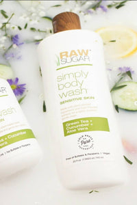 Raw Sugar Body Way for Sensitive Skin laying in water next to herbs, flowers and cucumbers