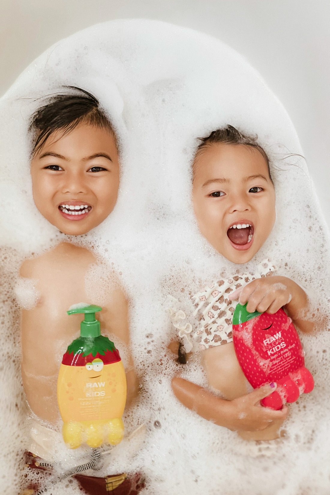 Two Kids holding Raw Sugar kids products surrounded by bubbles