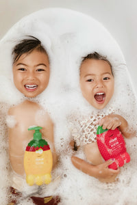 Two Kids playing in bath suds holding Raw Sugar kids products