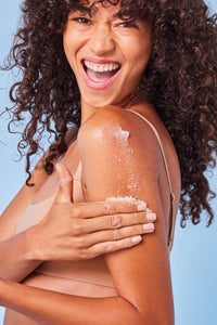 Woman applying Raw Sugar Sugar Scrub to her arm smiling