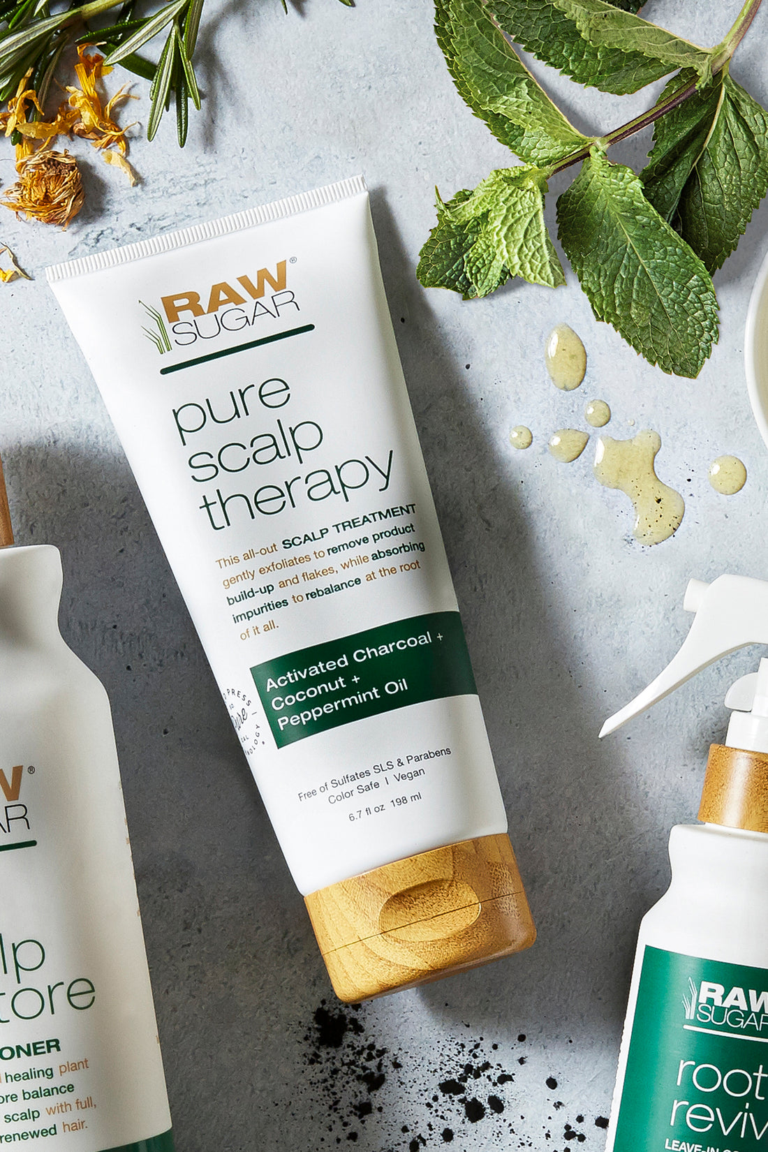 Raw Sugar Pure Scalp therapy tube lying next to fresh mint leaves, oil drops and partial photos of Root Revive and Scalp Restore