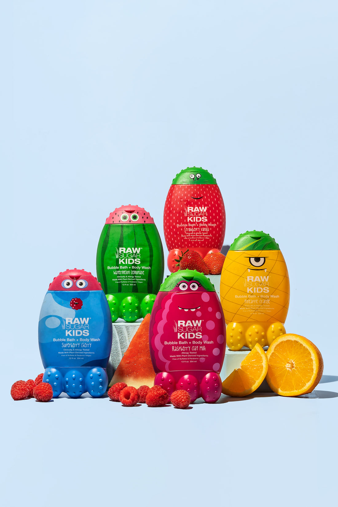 Group of all 5 colorful Raw Sugar Kids Bubble Bath Monsters with fresh raspberries , orange slice/half along with fresh watermelon