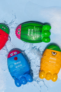 Raw Sugar Kids Monster bottles of bubble bath  lying flat being splashed with water