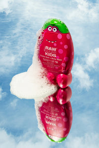 Artful display of Raw Sugar Kids Raspberry Oak Milk Bubble Bath Monster with foam and  reflection of same  floating in blue sky