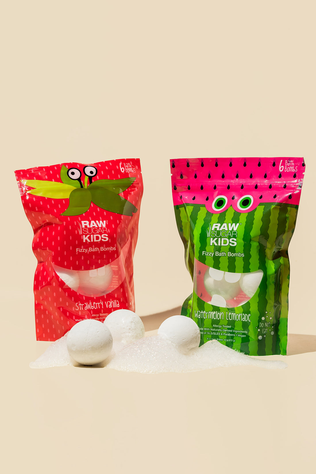 Two bags of both scents of Raw Sugar Kids Bath fiizzers with 3 fizzer balls in front bag on sugar 