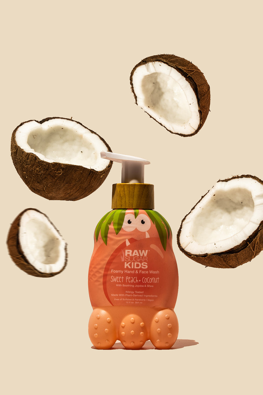 Raw Sugar Kids Foamy Hand + Face Wash, Sweet Peach + Coconut standing with floating fresh raw coconut halves
