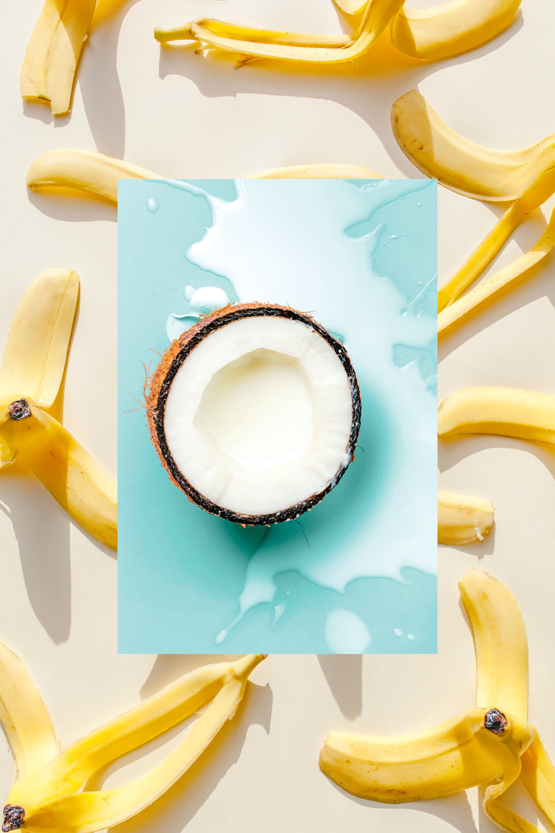 Half of a raw coconut with coconut milk splashed underneath and fresh banana peels