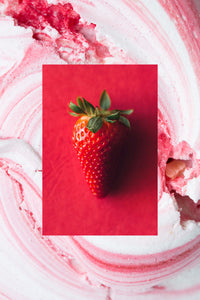 A single whole fresh strawberry on red background with strawberry cream swirl