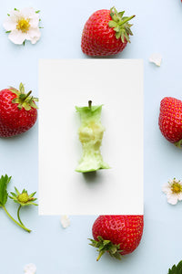 A single fresh green apple core with fresh strawberries and flowers