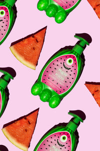 Kids Watermelon Lotion next to Watermelons on Pink Background