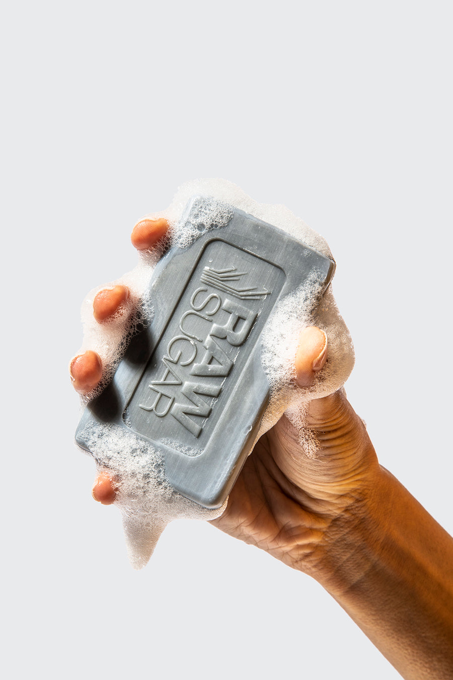 A hand holding bar of Raw Sugar Black Coconut + Sea Salt bar of soap