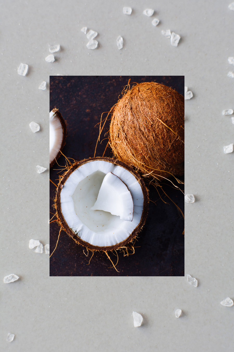 Half raw coconut next to whole coconut with large pieces of sea salt