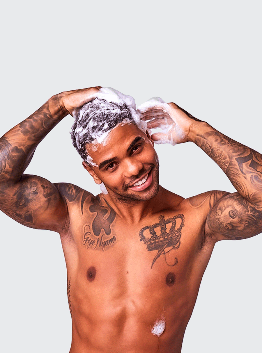 Smiling man washing hair with lots of suds